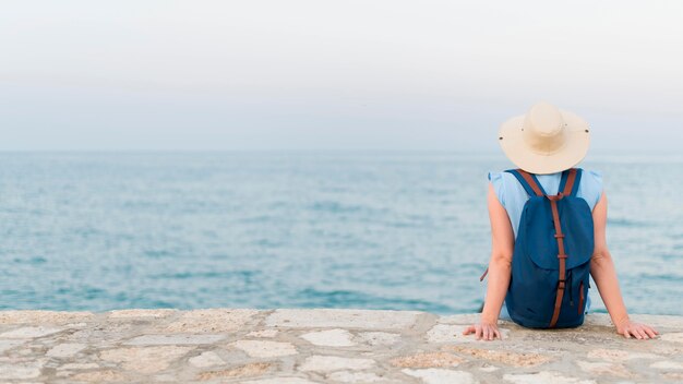 Back view of elder tourist woman enjoying the view of the ocean