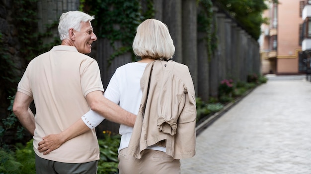 Back view of embraced older couple taking a walk outdoors