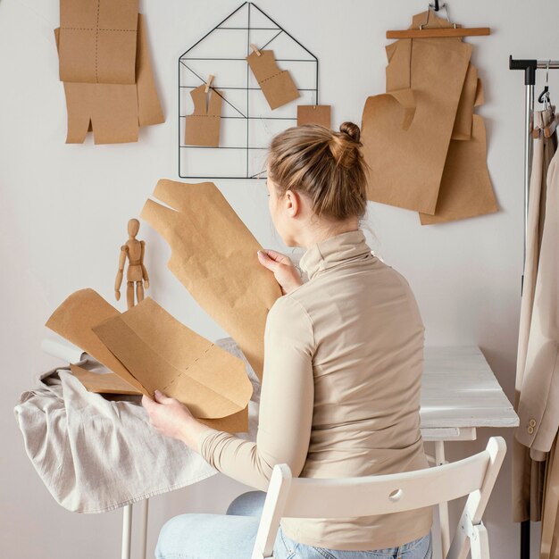 Back view of female tailor working on patterns in the studio