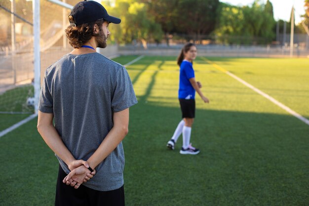 Back view football trainer helping kids