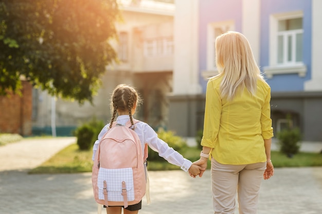 Free photo back view girl holding hands with mother