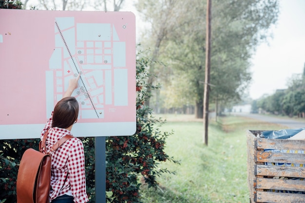 Free Photo back view girl with backpack checking a map in the park