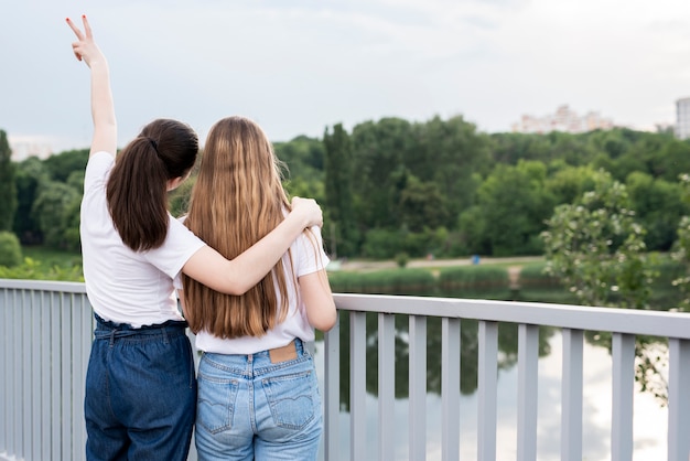 Free photo back view girlfriends posing on bridge