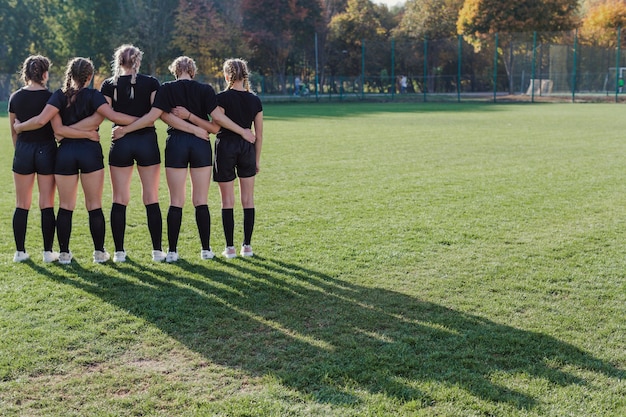 Back view girls standing in a football pitch