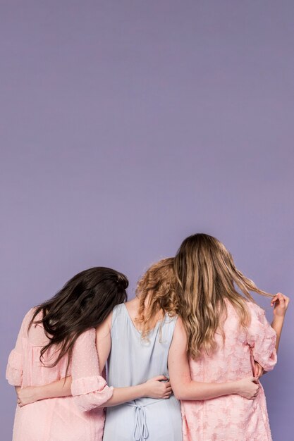 Back view of group of women holding each other with copy space