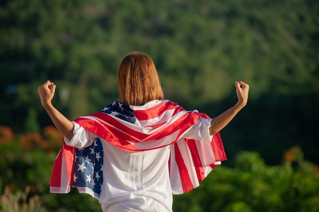 Free photo back view happy young woman posing with usa national flag standing outdoors at sunset.