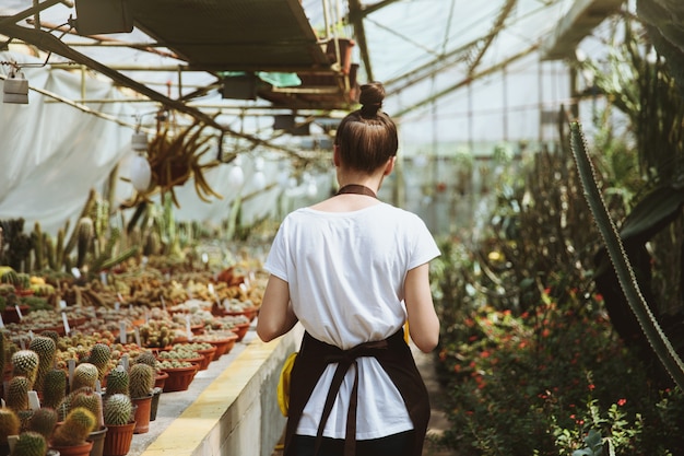 Free photo back view image of young woman standing in greenhouse