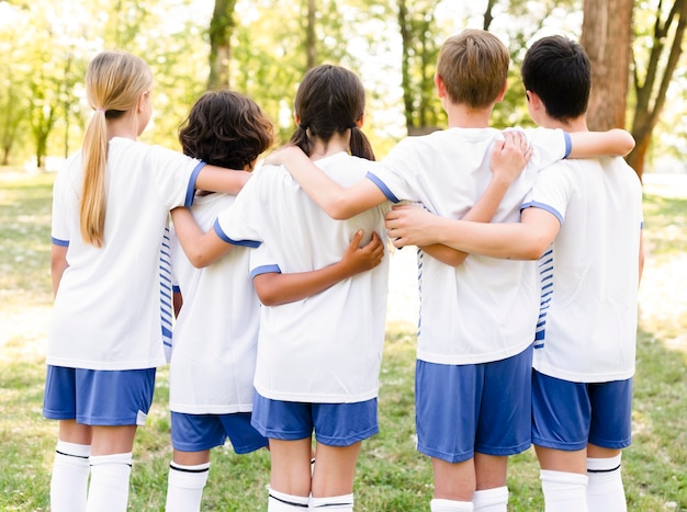 Back view kids in sportswear holding each other