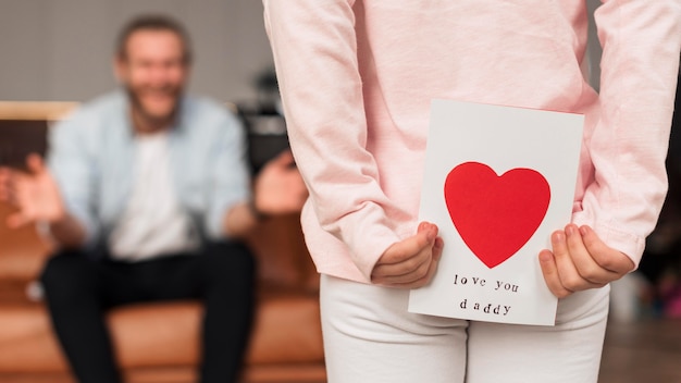 Back view of little girl giving father card for father's day