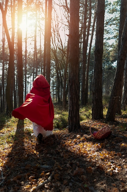 Free photo back view little red riding hood in the forest