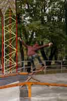 Free photo back view of man doing tricks with skateboard outdoors in the park