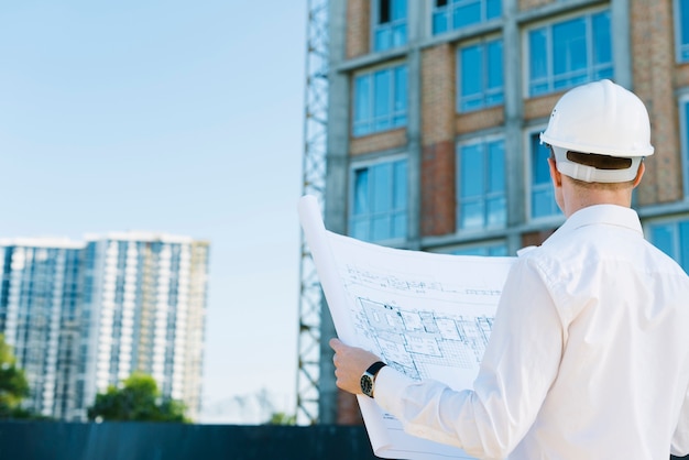 Free Photo back view man holding building plans