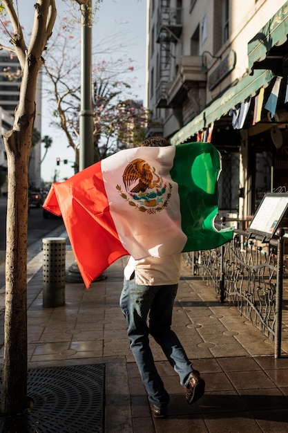 Back view man holding mexican flag outside