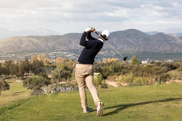 Free photo back view of man playing golf on the field