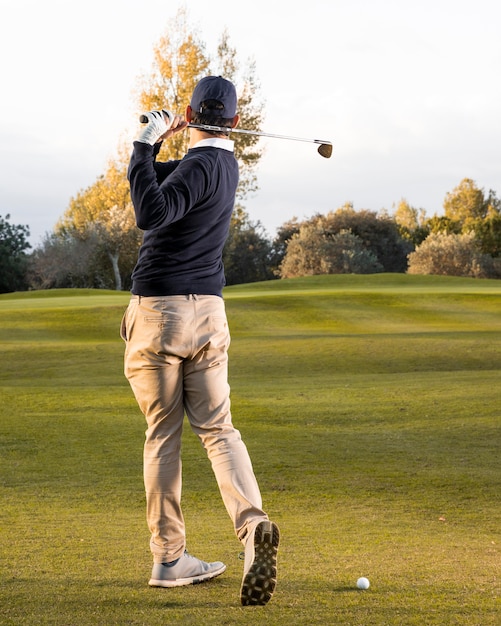 Back view of man playing on the grassy golf field