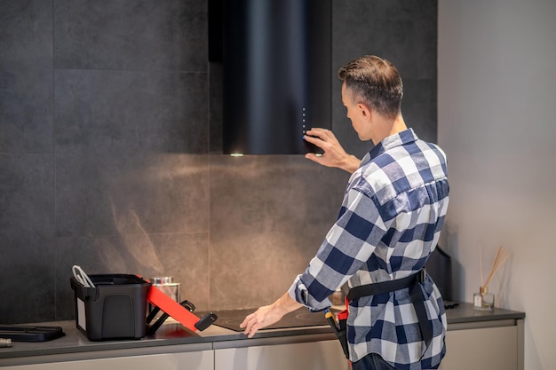 Free photo back view of man touching kitchen appliance hanging on wall