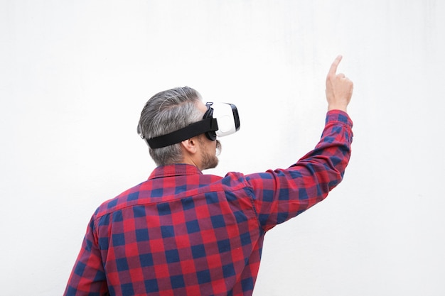 Free photo back view of man in vr headset pointing with finger