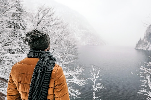 Back view of a man in winter clothes enjoying foggy winter near a mountain river