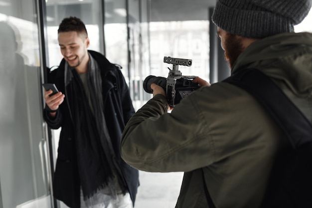 Free photo back view of photographer shooting handsome male model outside.