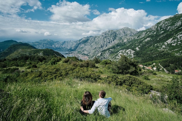 Back view of Romantic couple enjoy the view of the mountains on a sunny day in Montenegro