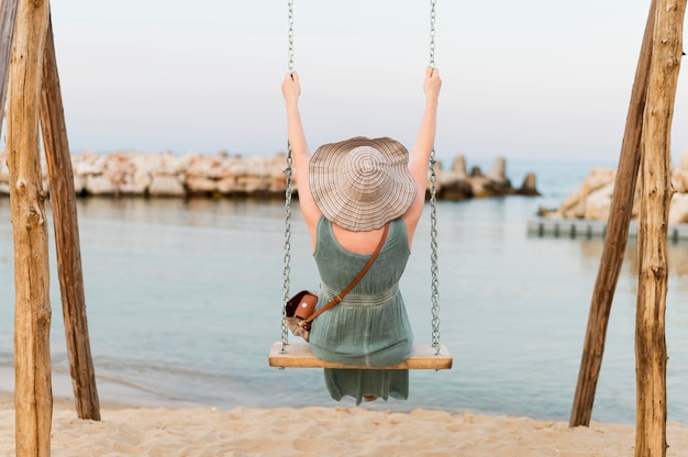 Free Photo back view of senior tourist woman in the beach swing