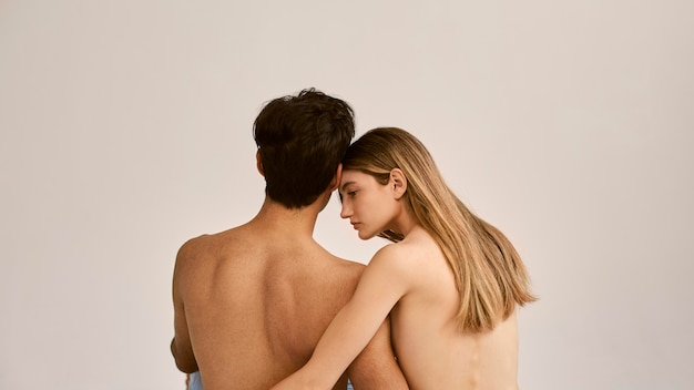 Back view of shirtless man and woman embraced