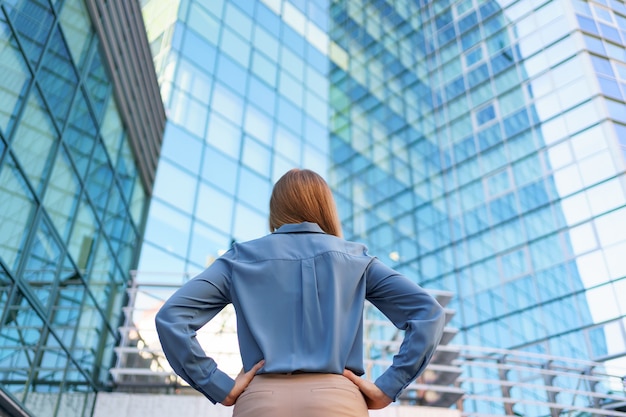 Back view of successful manager looking at business building of modern city.