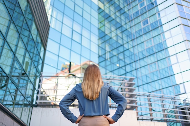 Back view of successful manager looking at business building of modern city.