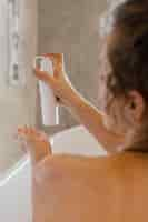 Free photo back view woman in bathtub with lotion