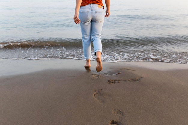 Free photo back view of woman on beach going in the water