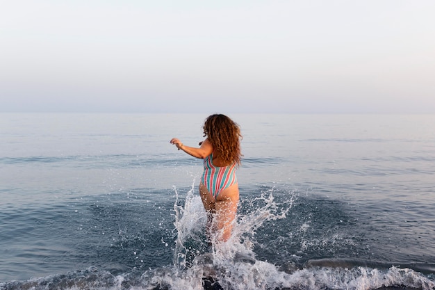 Free Photo back view of woman at the beach going in the water