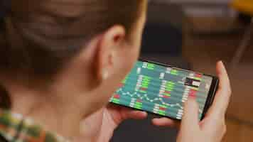 Free photo back view of woman checking stock trading using smartphone.