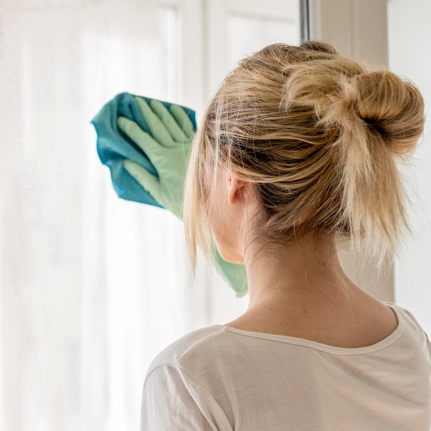 Back view of woman cleaning window with cloth