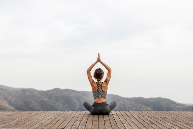 Back view of woman doing yoga outdoors