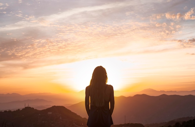 Back view of woman doing yoga while watching the sunset