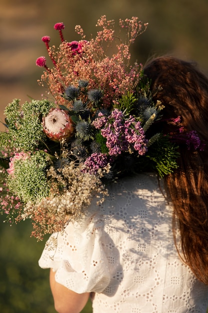 Free Photo back view woman holding beautiful flowers