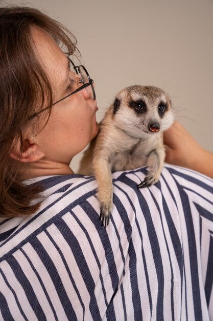 Back view woman holding meerkat