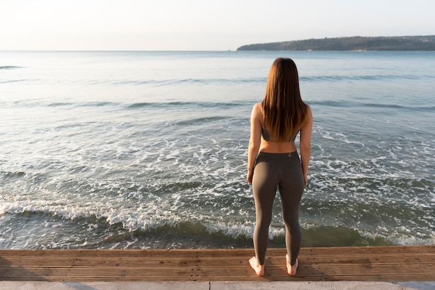 Free photo back view woman looking at the sea with copy space