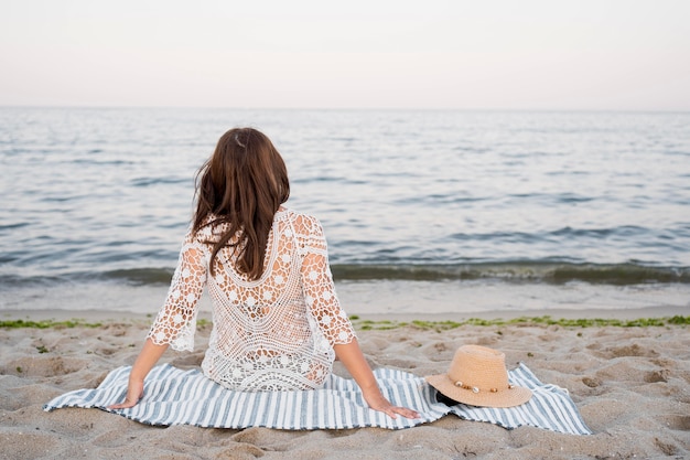 Free photo back view woman sitting on blanket