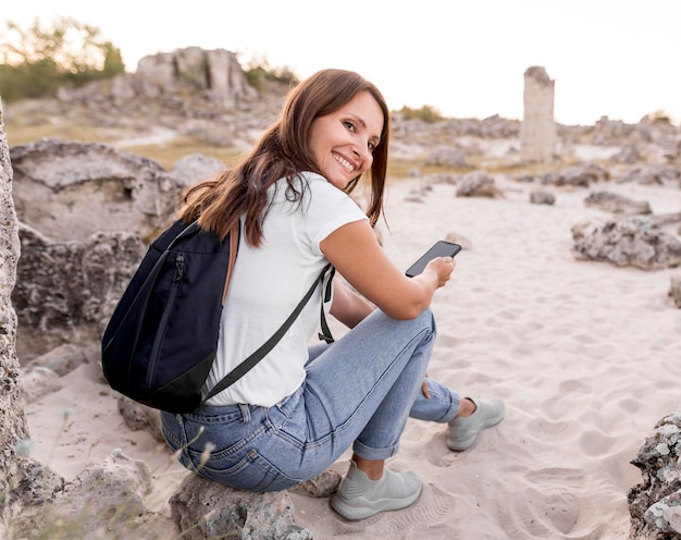 Back view woman smiling and sitting on a rock