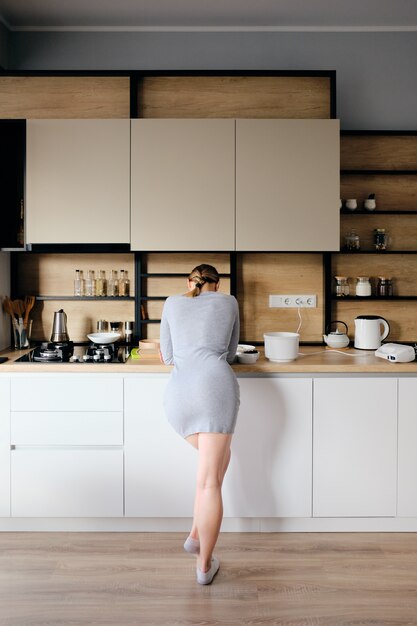 Back view of woman standing next to a modern kitchen