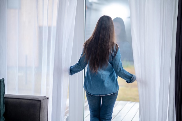 Free photo back view of woman standing near glass door