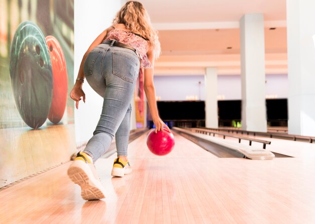 Back view woman throwing bowling ball