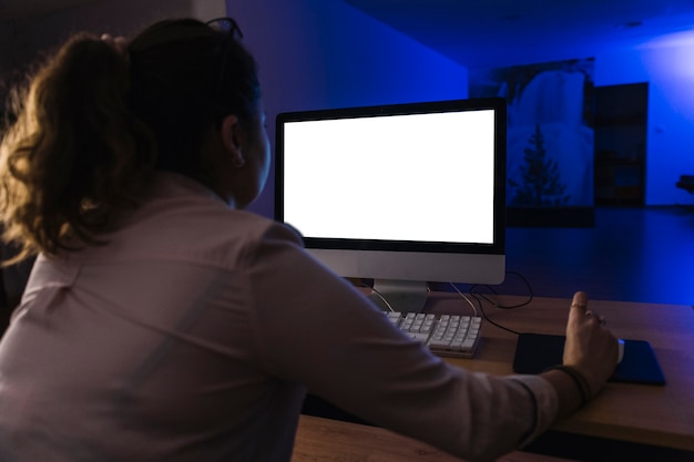 Back view woman using computer at night