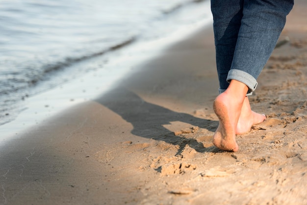 Free photo back view of woman walking barefoot on the beach