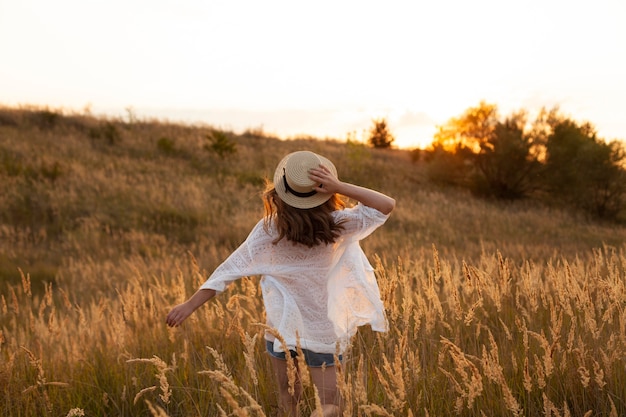 Free Photo back view of woman wearing hat and posing in the fields