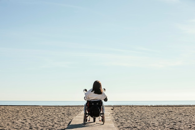 Back view of woman in a wheelchair at the beach