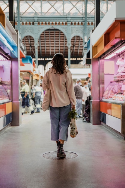 Free photo back view of woman with grocery bags at the market