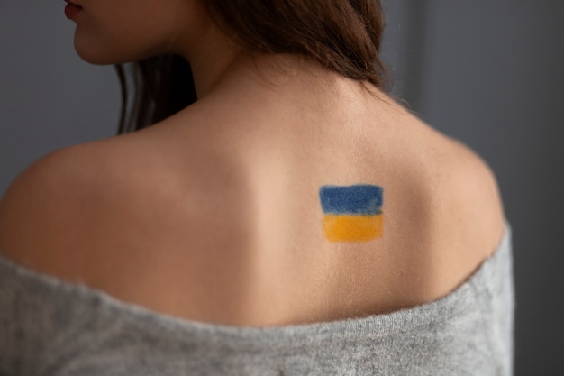 Free Photo back view woman with painted ukrainian flag