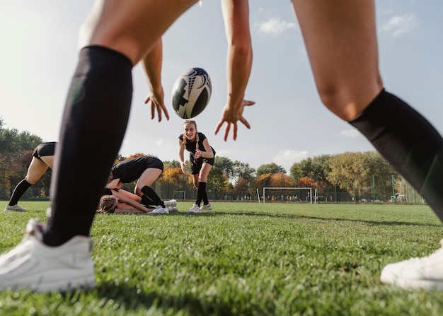 Back view women hands trying to catch a rugby ball